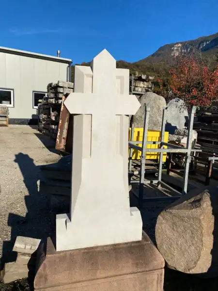 Restaurierter Grabstein aus hellem Marmor mit erhabenem Kreuz