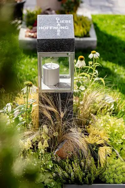 kleines Urnengrab aus schwarzem Granit mit Edelstahllaterne