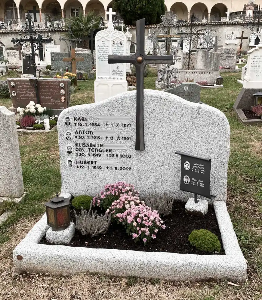 Grabstein aus weiß-schwarzem Granit mit Bronzekreuz