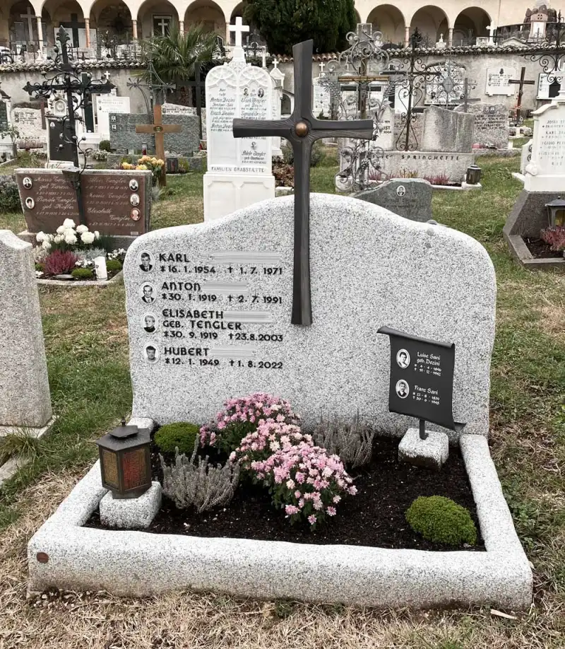 Grabstein aus weiß-schwarzem Granit mit Bronzekreuz