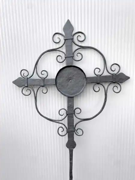 Zart gearbeitetes Kreuz aus Metall mit feinen Schnörkeln